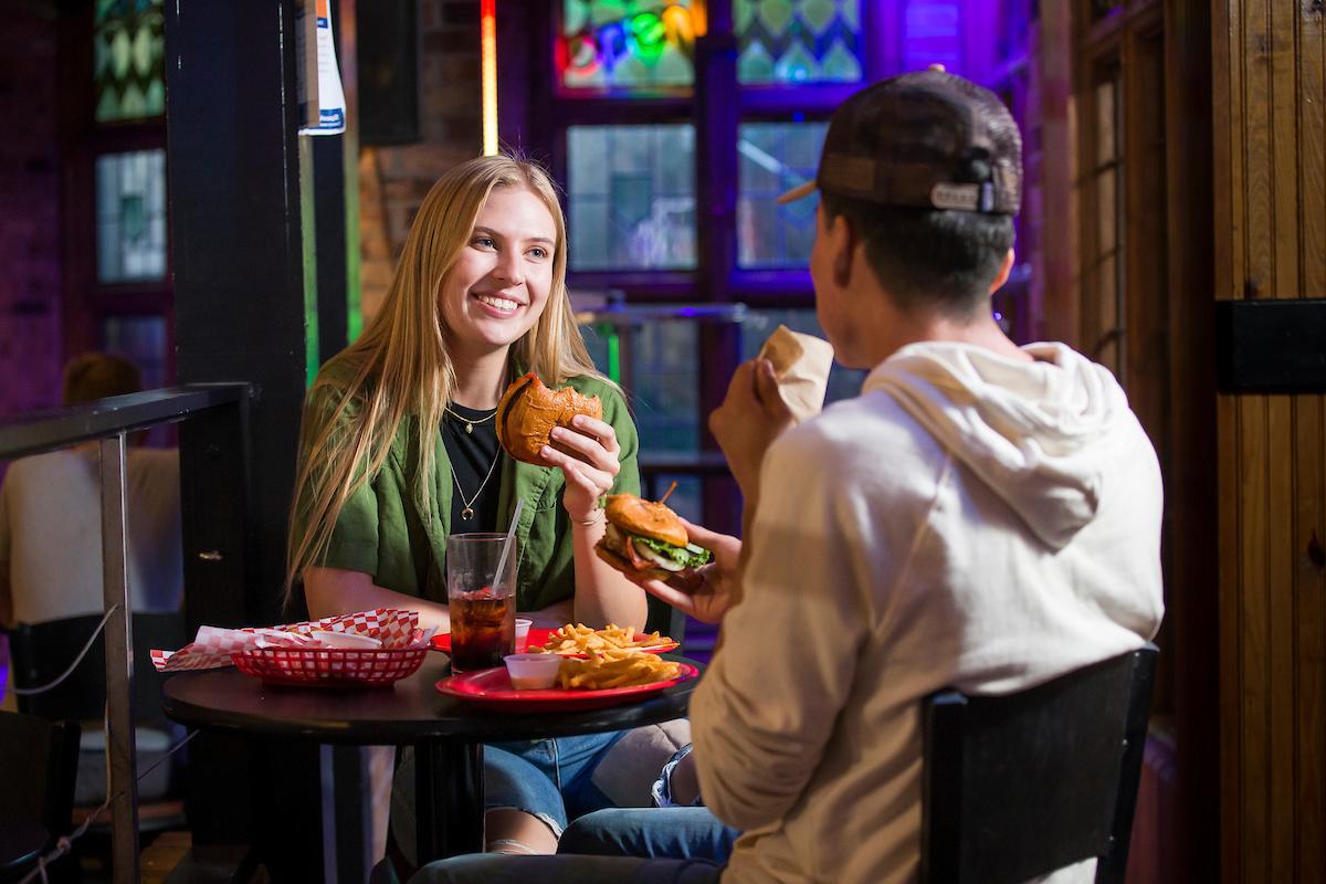 Two people eating a hamburger at a table