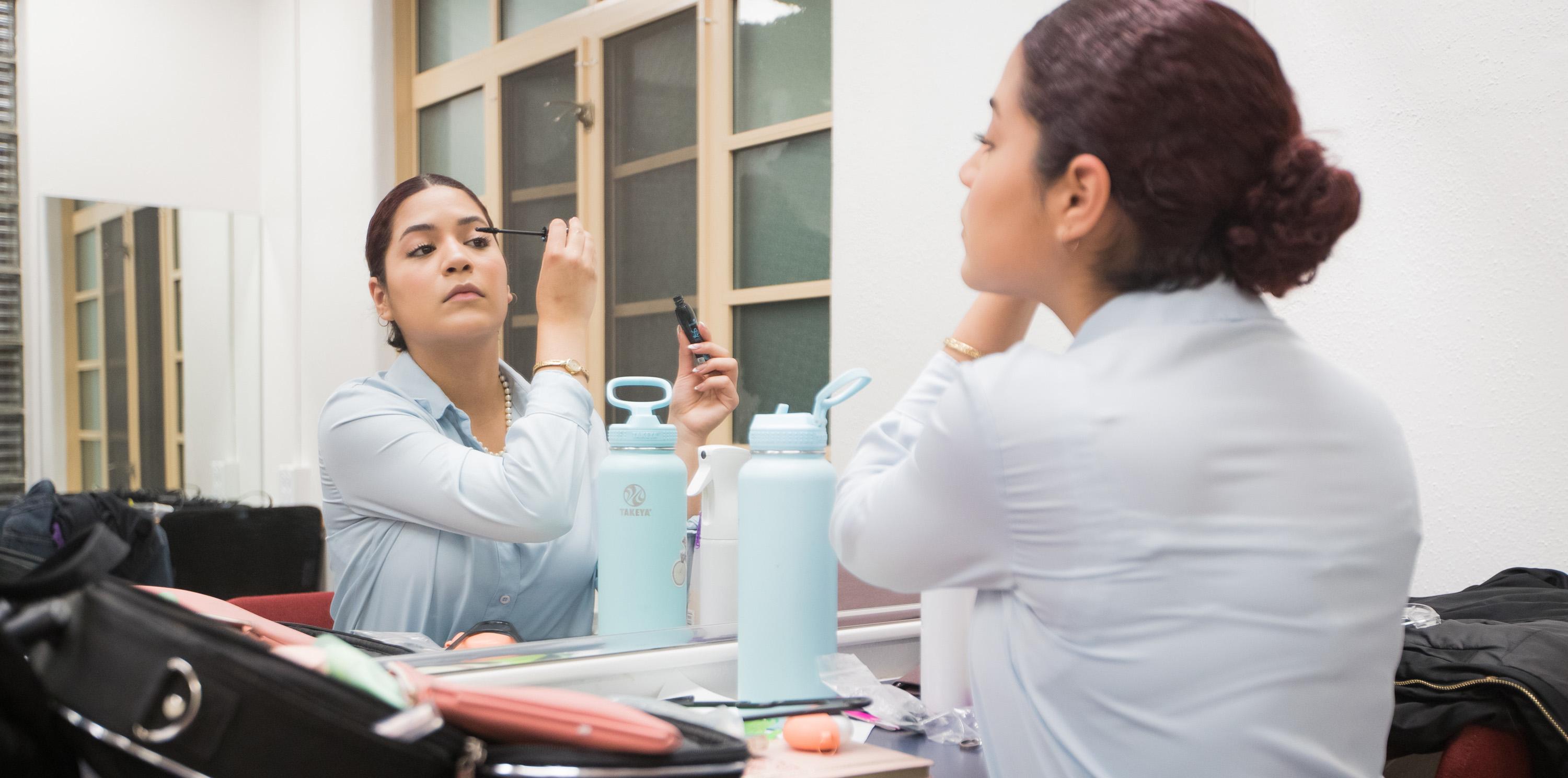 Andrea Camacho putting on mascara in the mirror